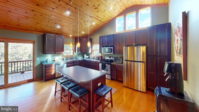 kitchen featuring a center island, stainless steel appliances, decorative light fixtures, and light hardwood / wood-style floors