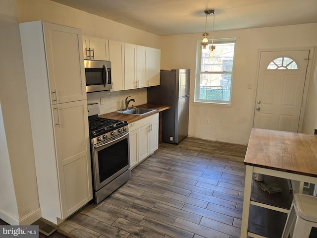 kitchen with tasteful backsplash, stainless steel appliances, white cabinets, sink, and dark hardwood / wood-style floors