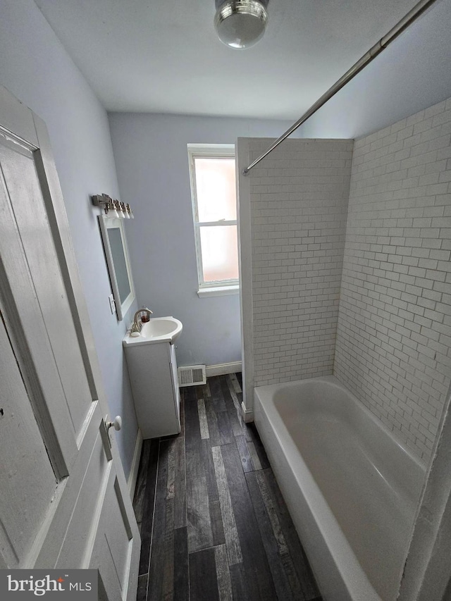 bathroom with tiled shower / bath combo, vanity, and hardwood / wood-style flooring