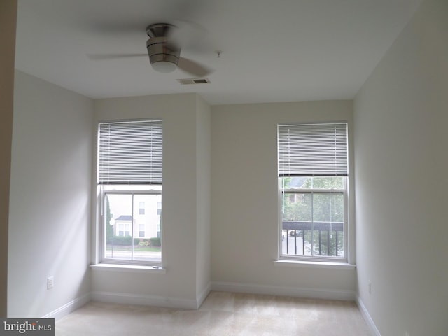 carpeted empty room featuring ceiling fan and plenty of natural light