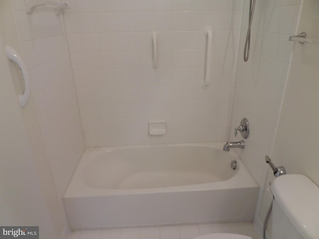 bathroom featuring tiled shower / bath, tile patterned flooring, and toilet