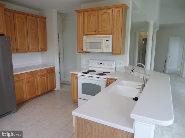 kitchen featuring sink, kitchen peninsula, decorative columns, white appliances, and light tile patterned floors