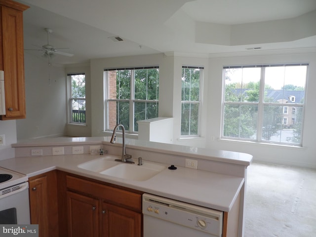 kitchen with sink, kitchen peninsula, light carpet, white appliances, and ceiling fan