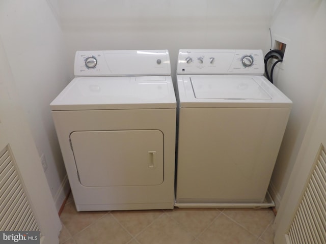 laundry area with washing machine and clothes dryer and light tile patterned floors