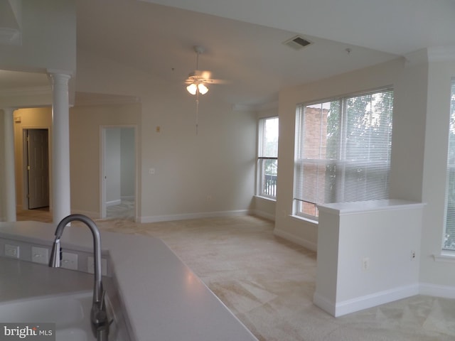 kitchen featuring decorative columns, light colored carpet, ceiling fan, and sink