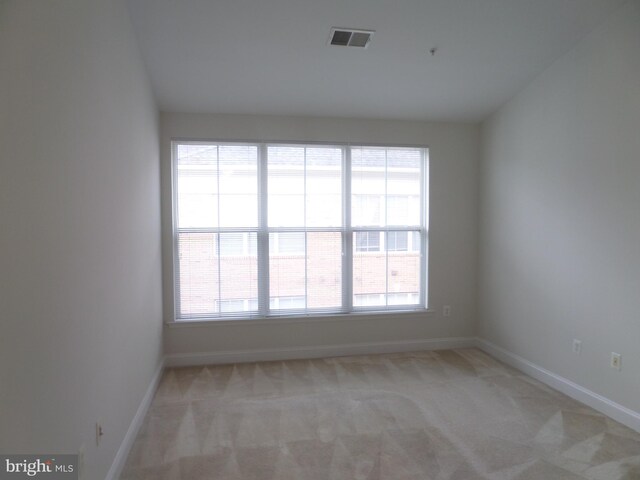 unfurnished room with light colored carpet and plenty of natural light