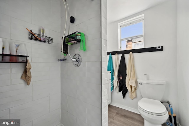 bathroom with wood-type flooring, tiled shower, and toilet