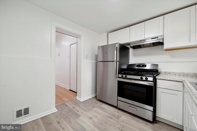 kitchen with stainless steel appliances, white cabinets, and light wood-type flooring