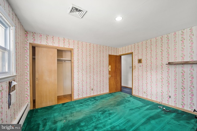 unfurnished bedroom with carpet floors, a closet, and a baseboard heating unit