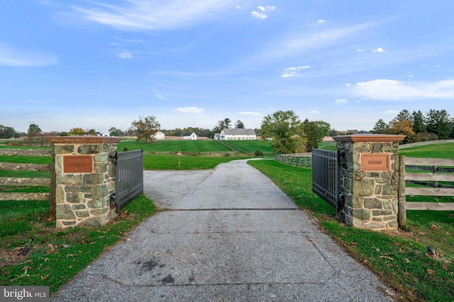 view of gate with a rural view and a lawn