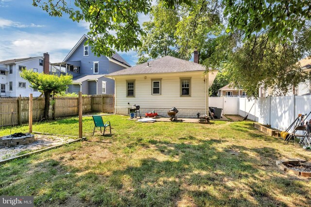 rear view of property featuring a yard and a fire pit