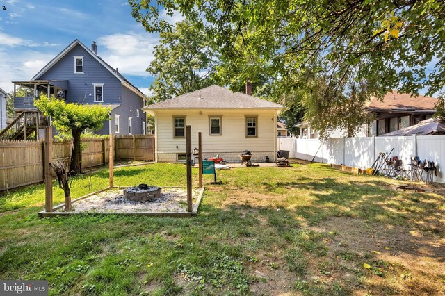 rear view of house with a patio area, a lawn, and a fire pit