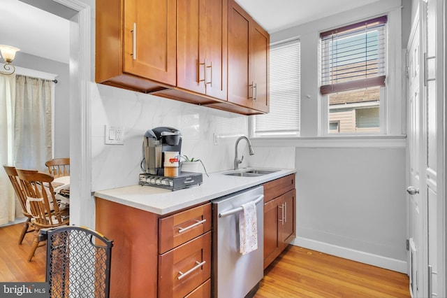 kitchen with decorative backsplash, light hardwood / wood-style floors, sink, and stainless steel dishwasher