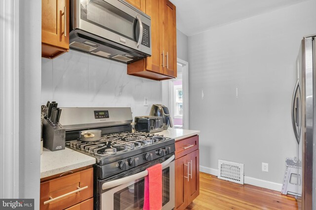 kitchen featuring light stone counters, light wood-type flooring, and stainless steel appliances