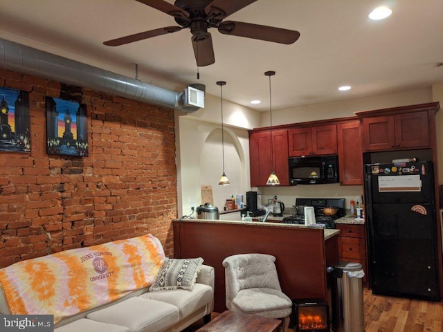 kitchen featuring light hardwood / wood-style floors, black appliances, kitchen peninsula, hanging light fixtures, and brick wall