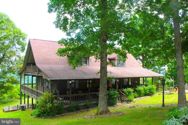 rear view of property featuring covered porch, a yard, a balcony, and central air condition unit