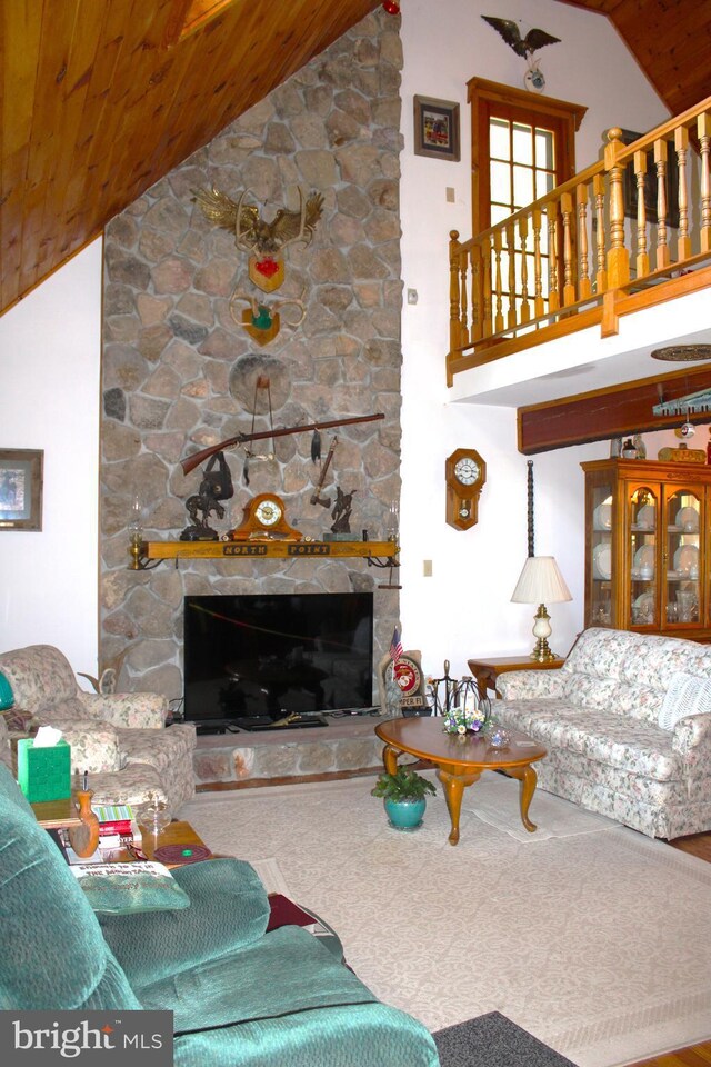 living room featuring a stone fireplace, wooden ceiling, and high vaulted ceiling