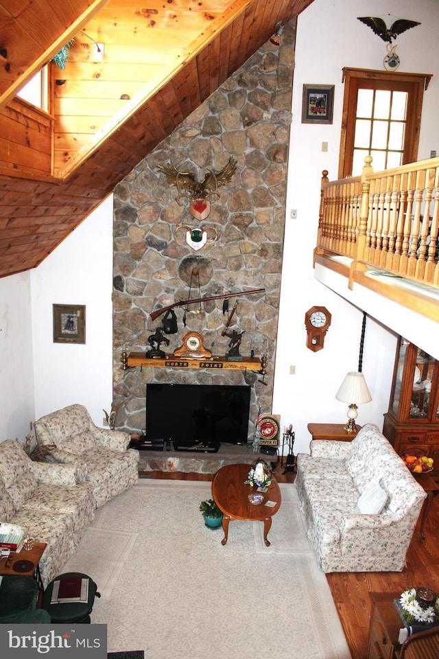 living room featuring wooden ceiling, a fireplace, and high vaulted ceiling