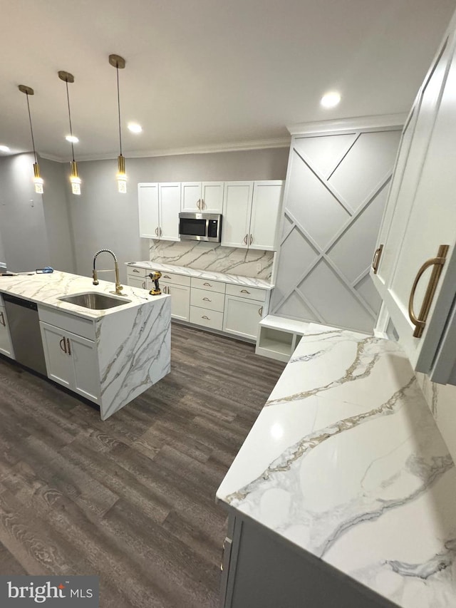 kitchen featuring sink, hanging light fixtures, appliances with stainless steel finishes, an island with sink, and white cabinets