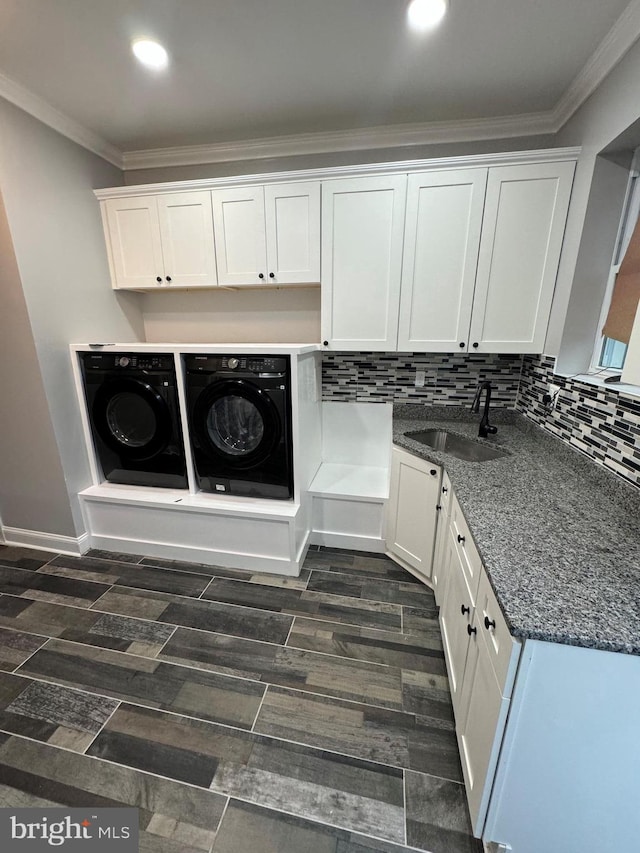 laundry room with sink, washer and clothes dryer, ornamental molding, and cabinets