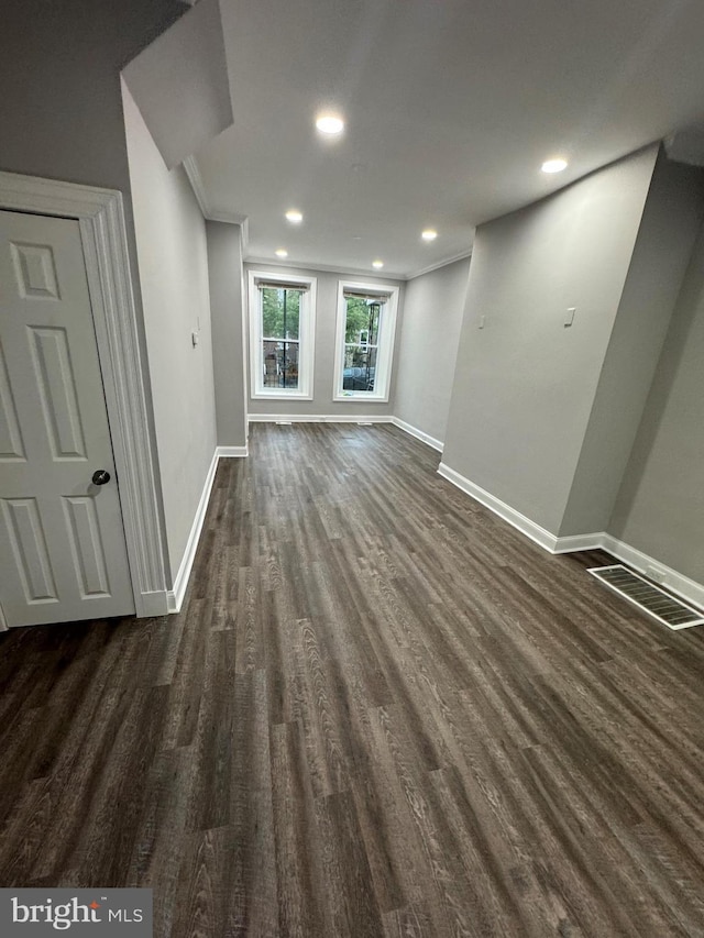 unfurnished living room with dark wood-type flooring and ornamental molding