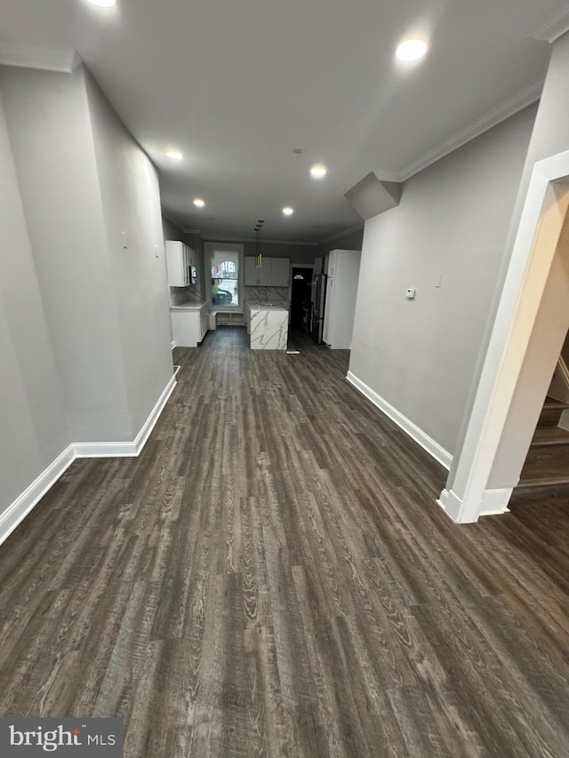 unfurnished living room with dark hardwood / wood-style flooring and crown molding