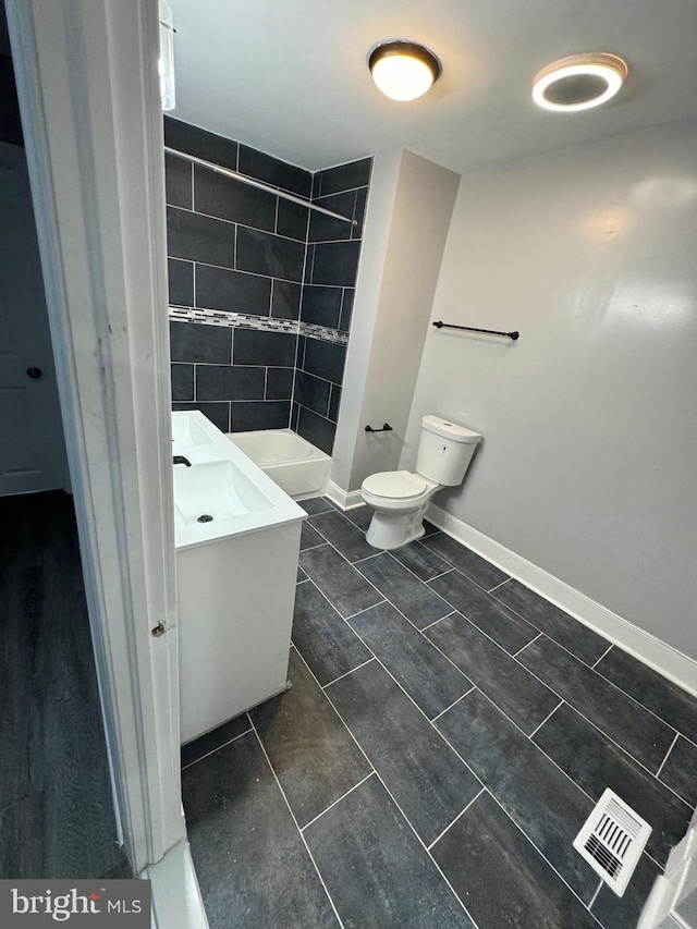 bathroom featuring tiled shower, tile patterned floors, toilet, and vanity