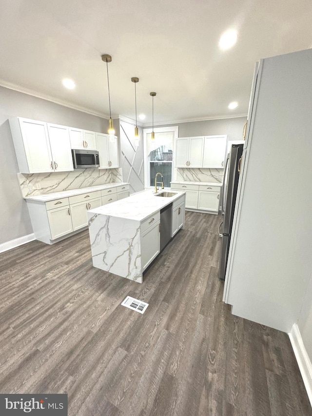 kitchen with pendant lighting, appliances with stainless steel finishes, white cabinetry, light stone counters, and decorative backsplash