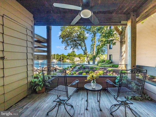 deck with a water view and ceiling fan