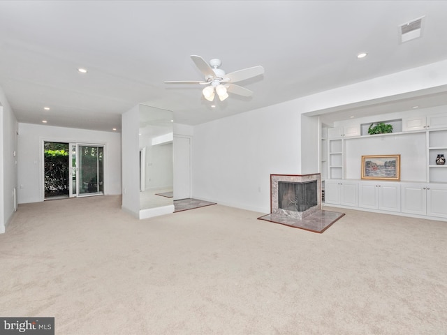 unfurnished living room with a multi sided fireplace, built in shelves, light colored carpet, and ceiling fan