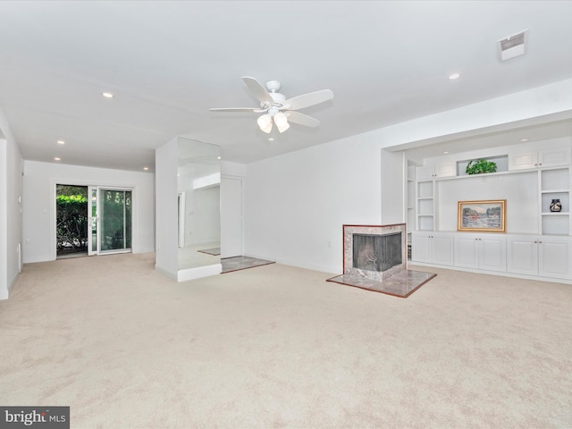 unfurnished living room featuring a multi sided fireplace, light carpet, built in features, and ceiling fan