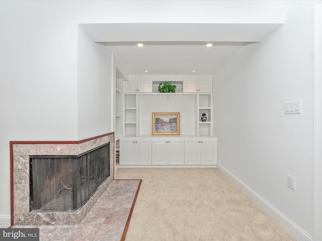 unfurnished living room with a multi sided fireplace, built in shelves, and light carpet