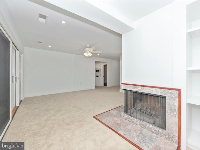 living room featuring a tiled fireplace, ceiling fan, and carpet floors