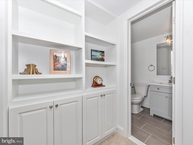 bathroom with built in shelves, vanity, and toilet