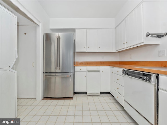 kitchen featuring white dishwasher, stacked washer / drying machine, stainless steel fridge, and white cabinetry