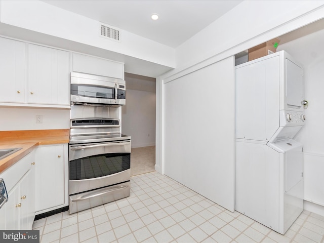 kitchen with white cabinets, range, and stacked washer and clothes dryer