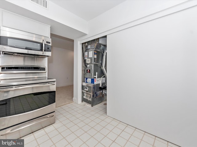 kitchen featuring range, heating unit, and white cabinetry