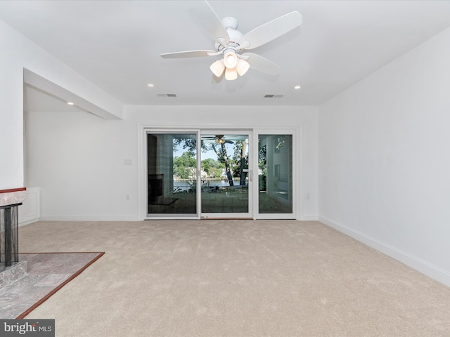 unfurnished living room with ceiling fan, light colored carpet, and a fireplace