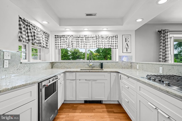 kitchen featuring sink, plenty of natural light, light wood-type flooring, white cabinets, and appliances with stainless steel finishes