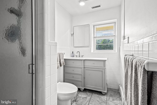 bathroom with vanity, a shower with shower door, tile walls, and toilet