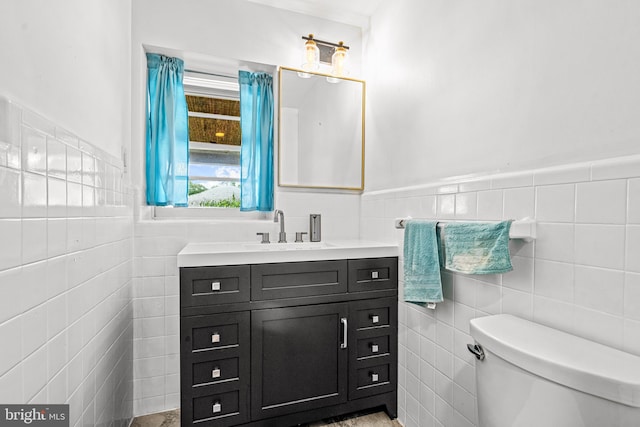 bathroom with vanity, toilet, and tile walls