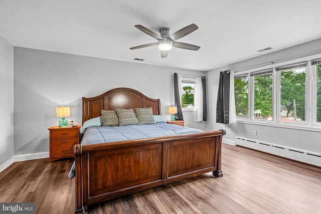 bedroom featuring baseboard heating, ceiling fan, and hardwood / wood-style floors