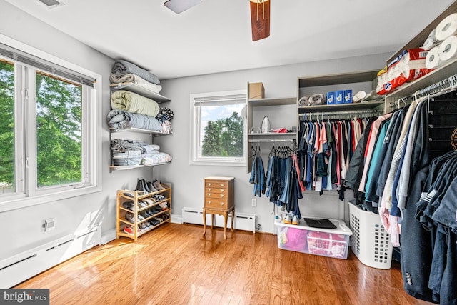 spacious closet with ceiling fan, wood-type flooring, and a baseboard heating unit