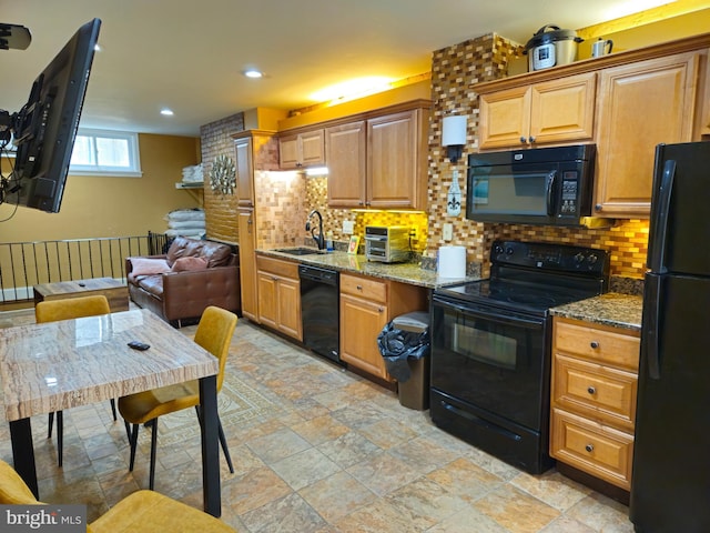 kitchen featuring sink, backsplash, light stone counters, and black appliances