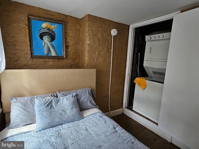 bedroom featuring stacked washer / drying machine and dark hardwood / wood-style floors