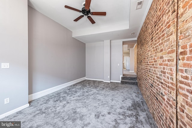 unfurnished living room featuring carpet, ceiling fan, and brick wall