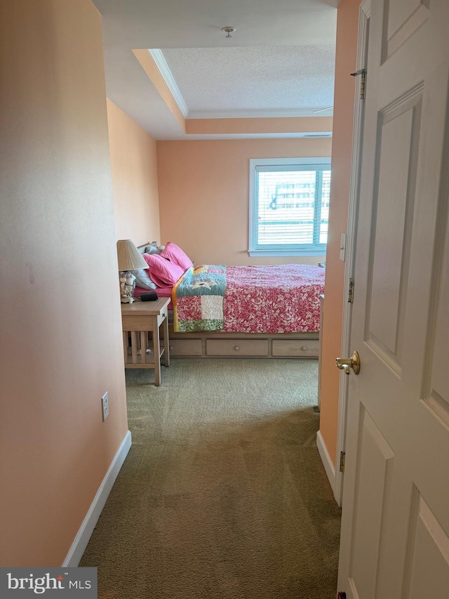 carpeted bedroom with a textured ceiling, crown molding, and a tray ceiling