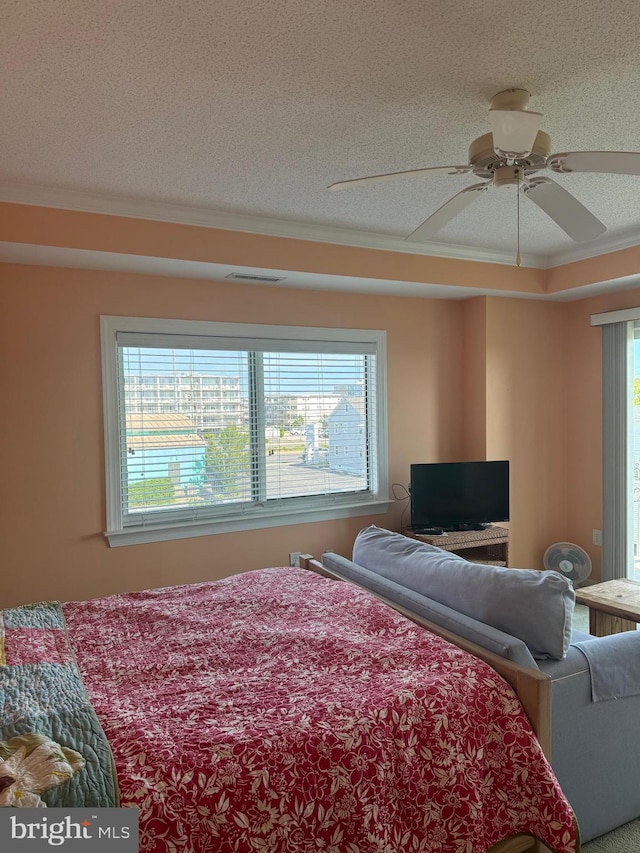 bedroom featuring a textured ceiling, ceiling fan, and ornamental molding