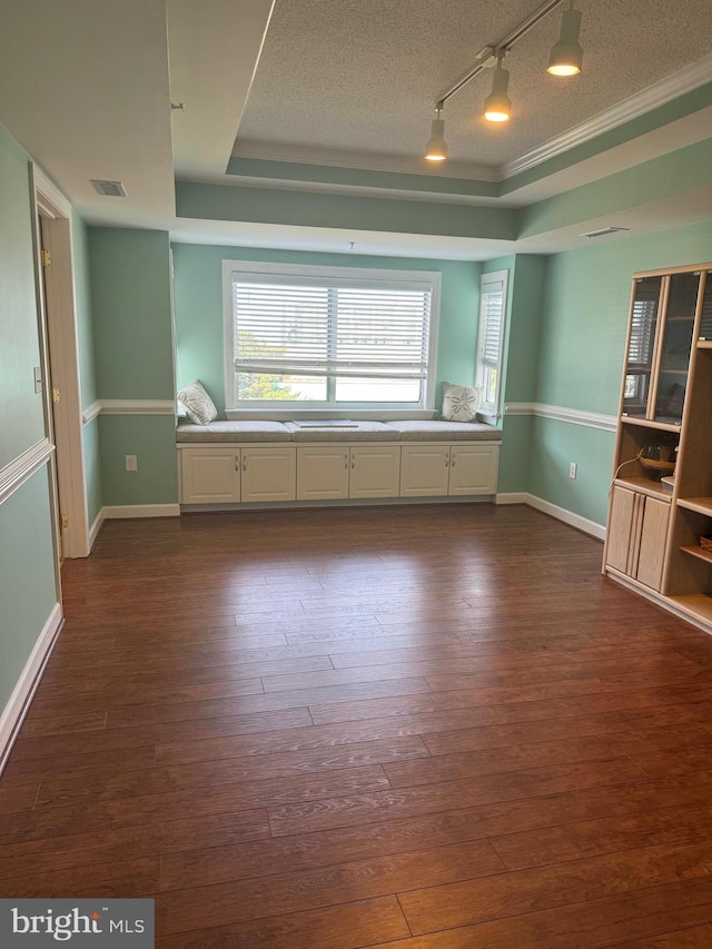 unfurnished room featuring a raised ceiling, dark hardwood / wood-style floors, a textured ceiling, and track lighting