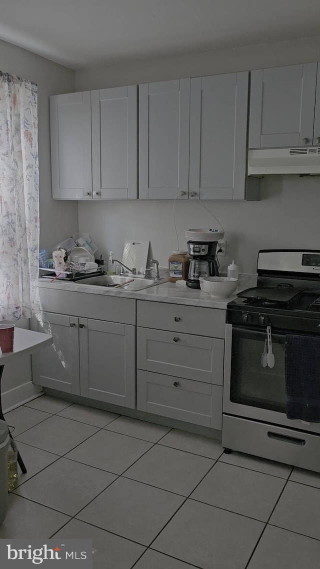 kitchen featuring light tile patterned floors, white cabinetry, and gas range gas stove